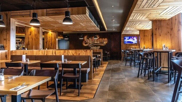 A restaurant interior with wooden accents, tables, and chairs. - Hotel D1 (Ostrovacice)