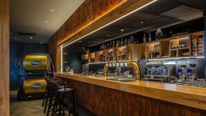 A bar area with a wooden counter, bar stools, and a grill. - Hotel D1 (Ostrovacice)