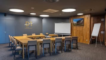 Ein Konferenzraum mit einem langen Tisch, Stühlen, einer Tafel und einem Projektor.