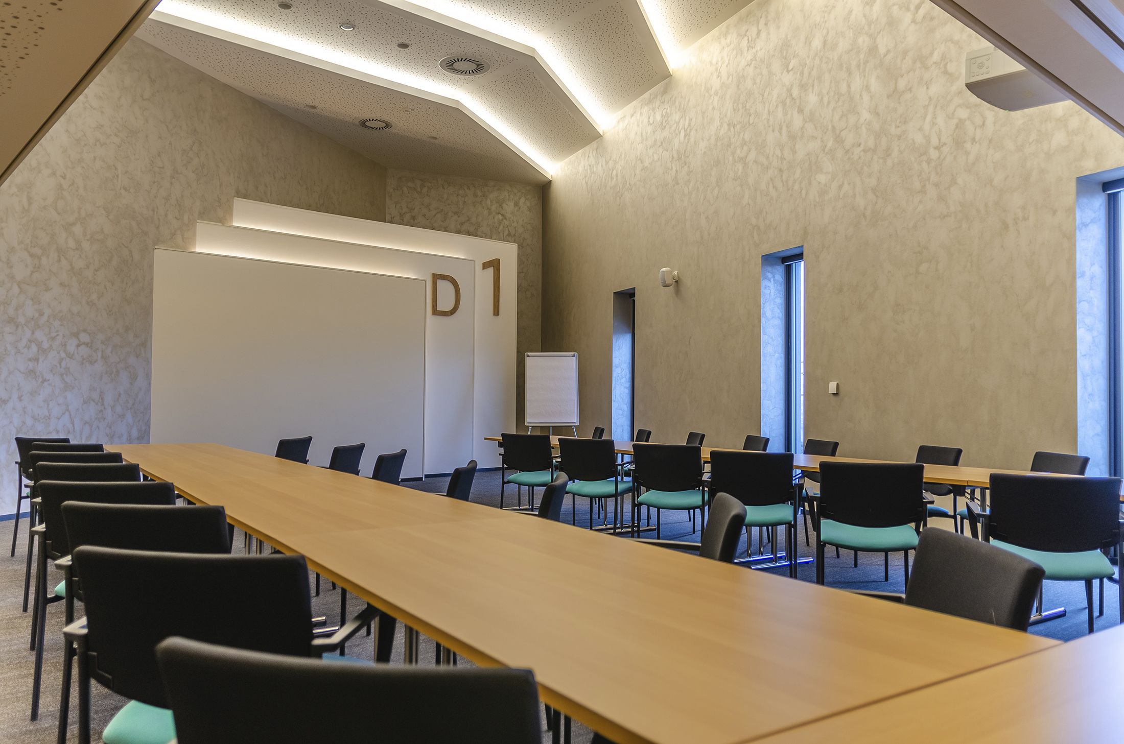 Ett konferensrum med ett långt bord, stolar, en whiteboard och en dörr med skylten "D1".