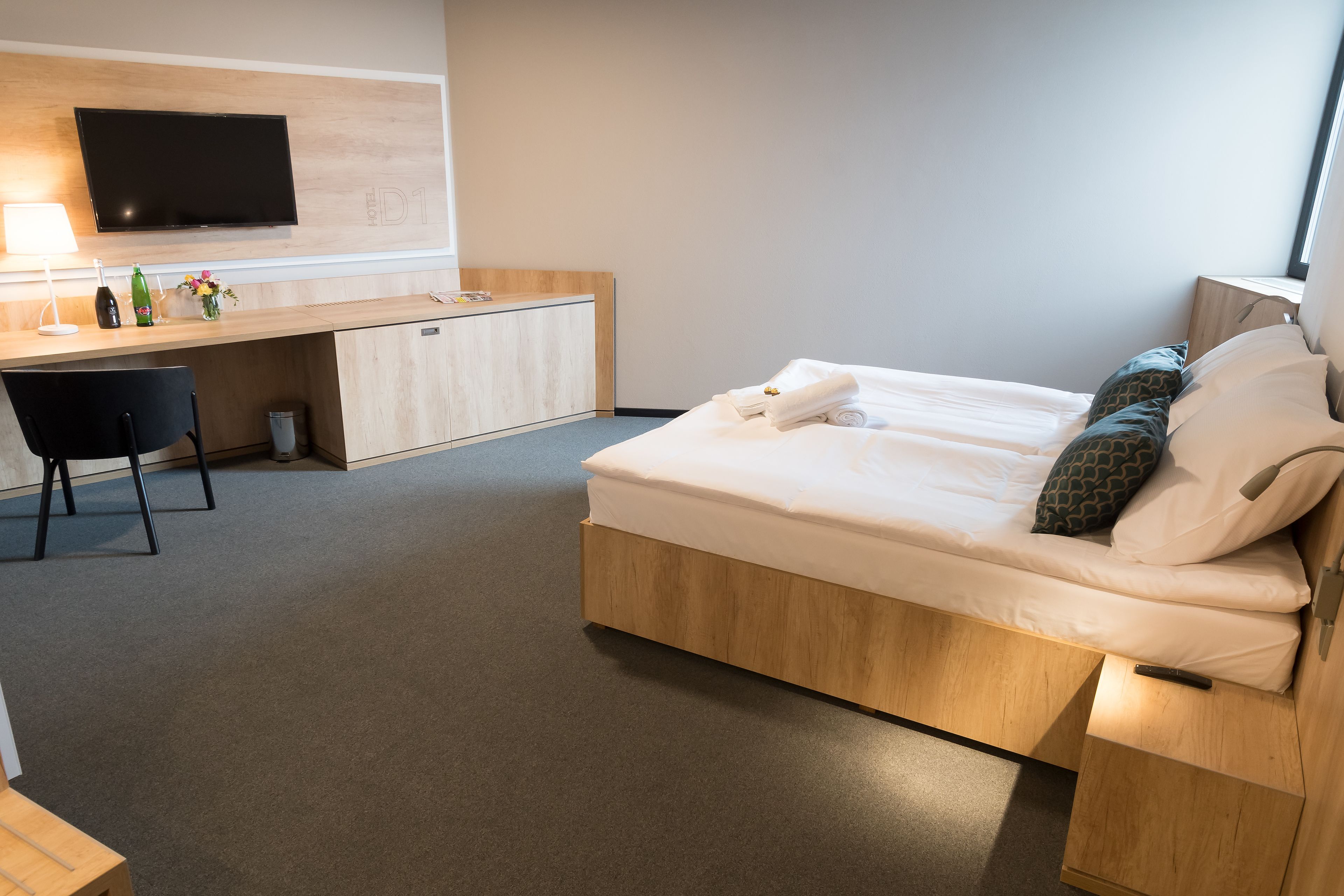 A modern hotel room with a bed, a desk, and a TV.