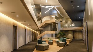A modern interior with a central staircase, seating area, and a mezzanine level. - Hotel D1 (Ostrovacice)