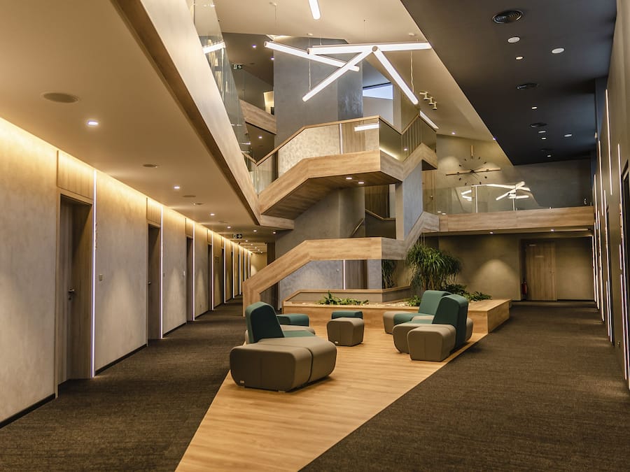 Een modern interieur met een centrale trap, zithoek en een entresol.