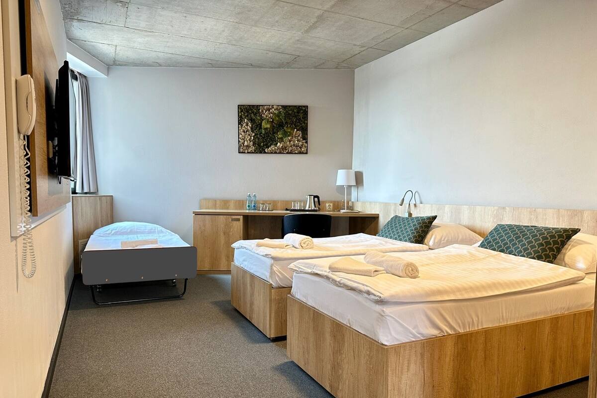 Une chambre d’hôtel avec deux lits, un bureau, une chaise, un téléphone et un tableau au mur.