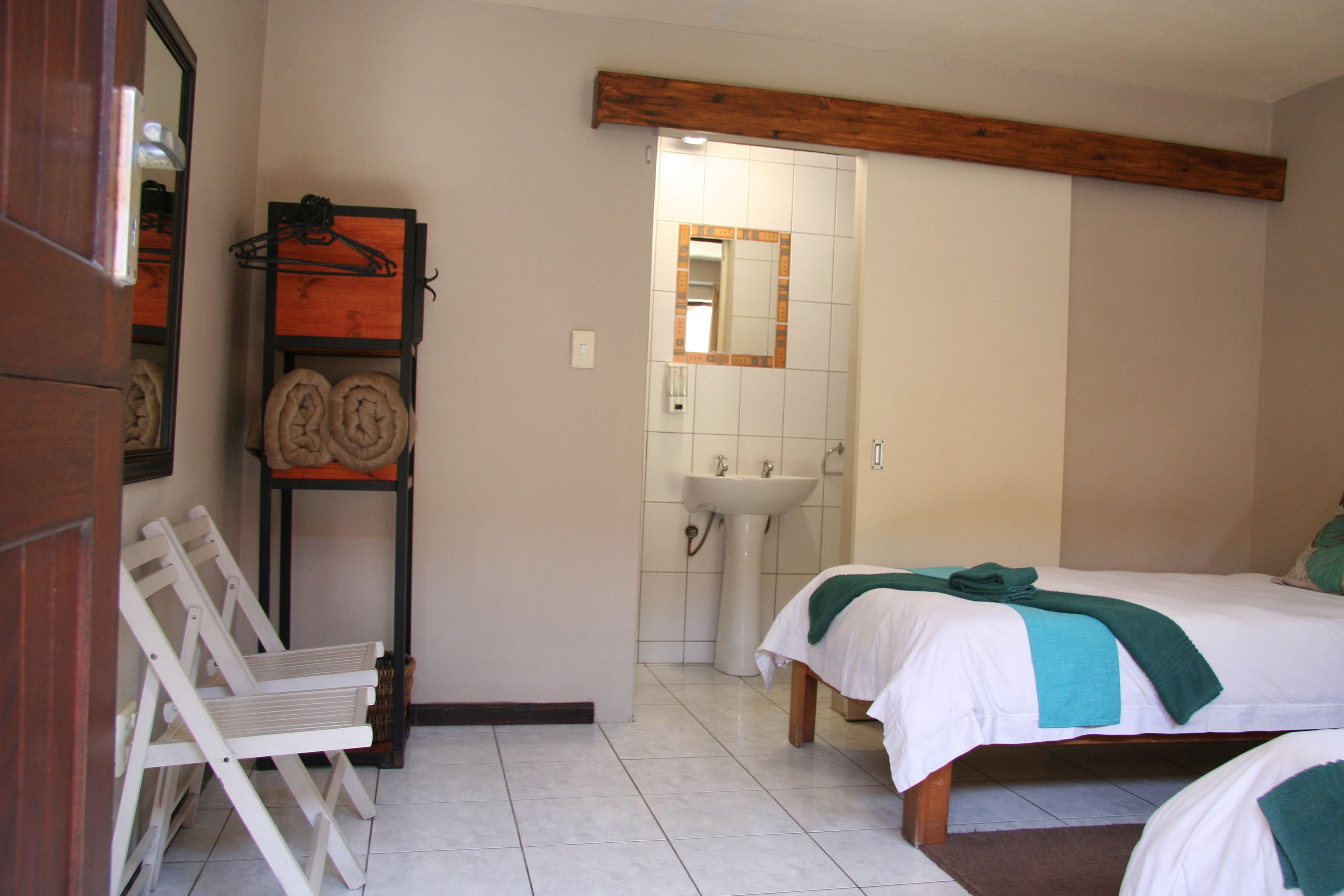 Ein Schlafzimmer mit zwei Betten, einem Holzbalken an der Decke, einem weißen Waschbecken und einem Spiegel.