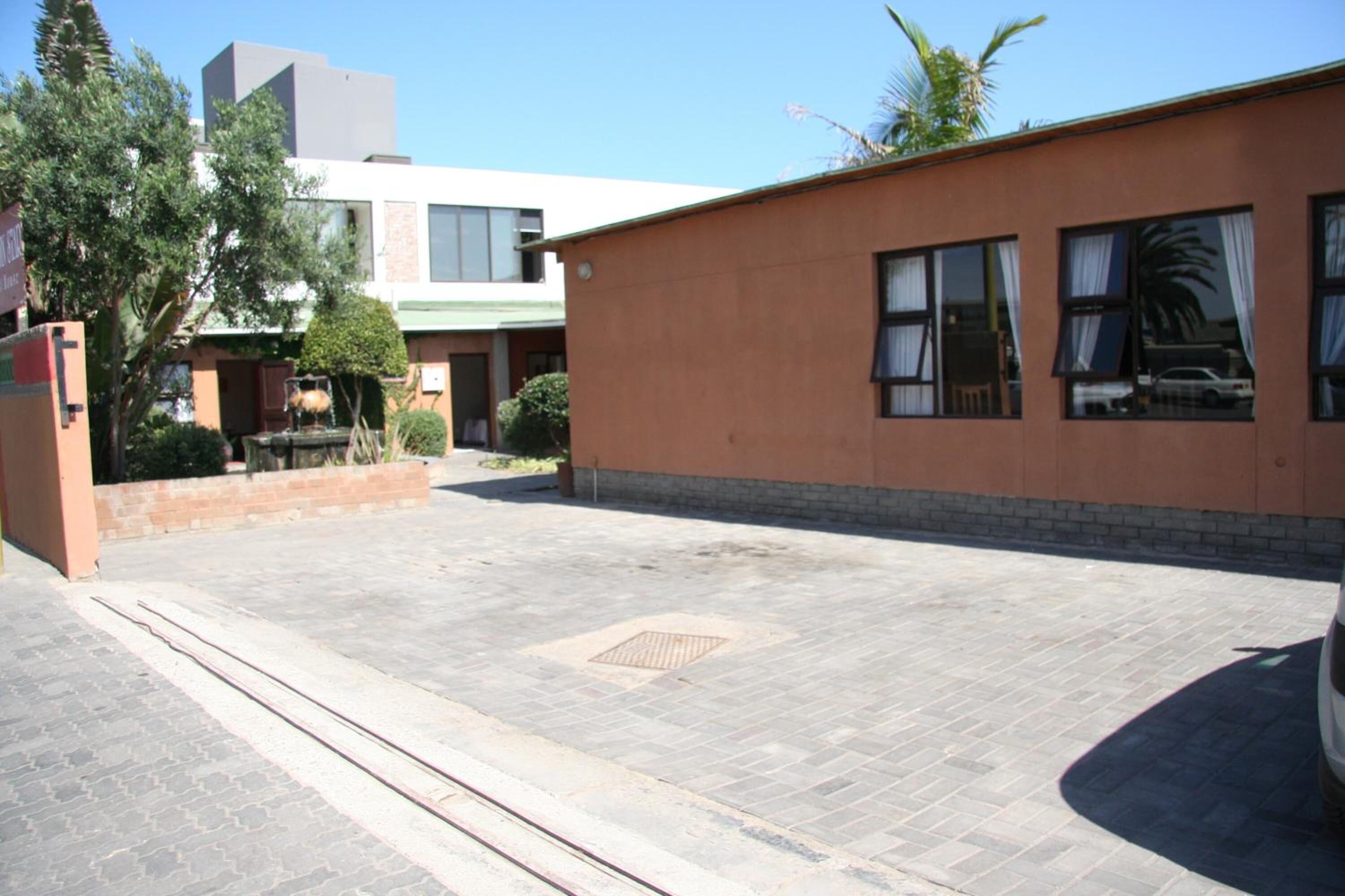 A building with a paved courtyard, a manhole cover, and a parked car.