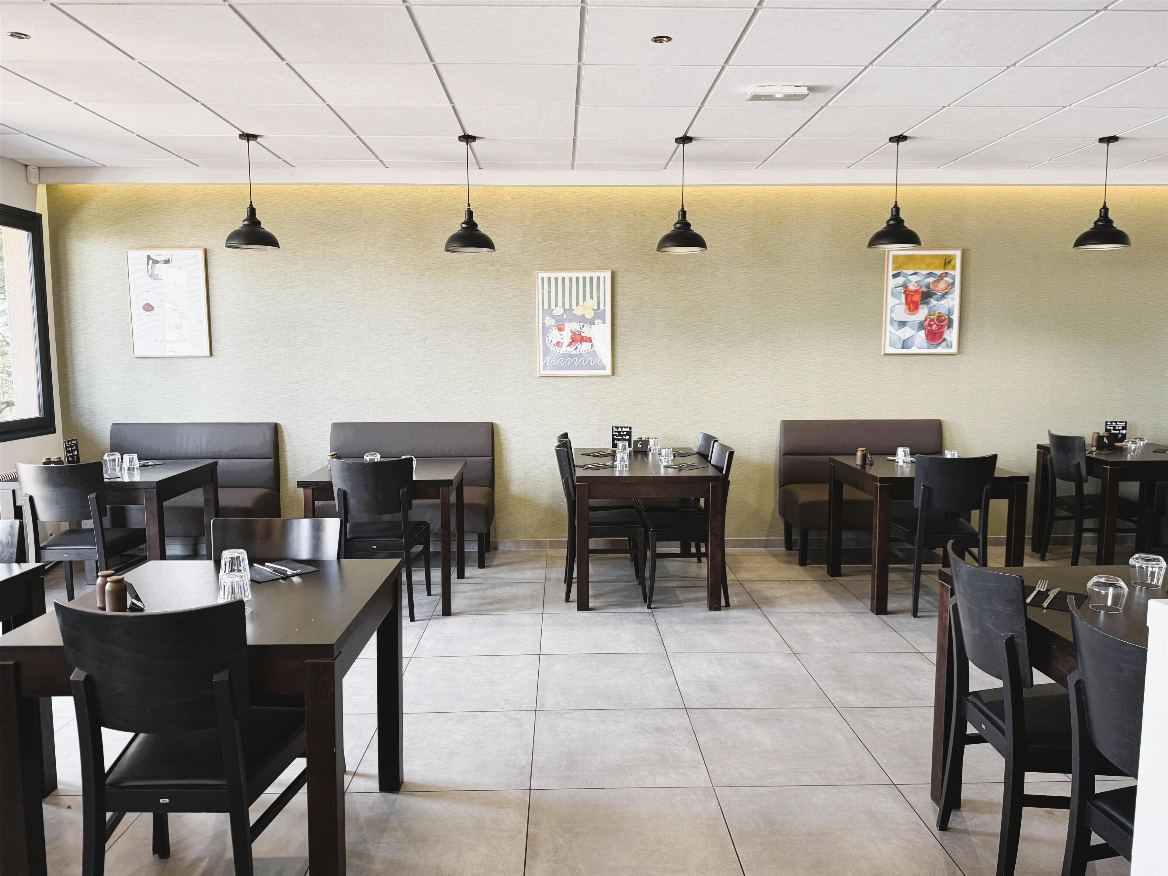 A restaurant with booths and tables, pendant lighting, and artwork on the walls.