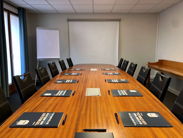 A conference room with a long wooden table, black chairs, and name cards. - Kyriad Sens (Malay-le-Grand)