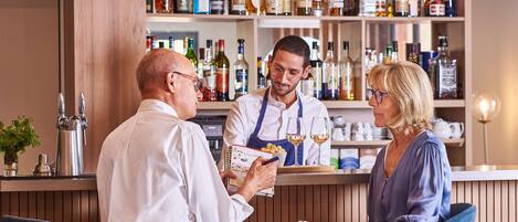 Een bar met een barman die drankjes serveert aan twee gasten.