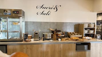 A bakery counter with a display case, a coffee machine, and various baking tools.
