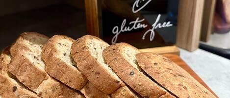 Slices of gluten-free bread on a wooden board with a sign stating "Pain dans gluten free."