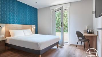 A modern hotel room with a bed, a desk, and a chair.