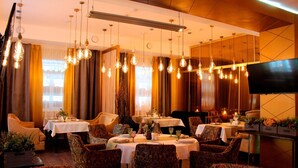 Un restaurant avec plusieurs tables et chaises, un éclairage au plafond et un téléviseur fixé au mur.