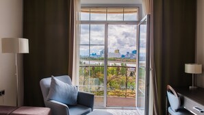 Une chambre d’hôtel avec un balcon, un bureau, une chaise et une lampe.