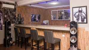 A bar area with wooden paneling, a counter, and multiple speakers. - Duckland Hotel and Suites Ltd (Ikorodu)