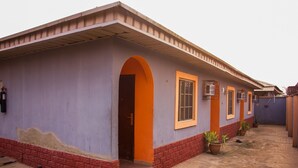 A building with a purple exterior, orange door, and windows. - Duckland Hotel and Suites Ltd (Ikorodu)