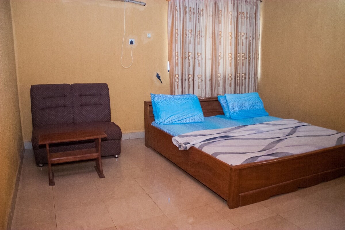 Un dormitorio con cama, sofá y mesita de noche de madera.