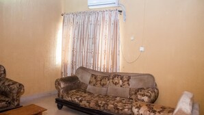 A living room with a sofa, a wooden coffee table, and a patterned curtain. - D Jos Hotel (Ijede)
