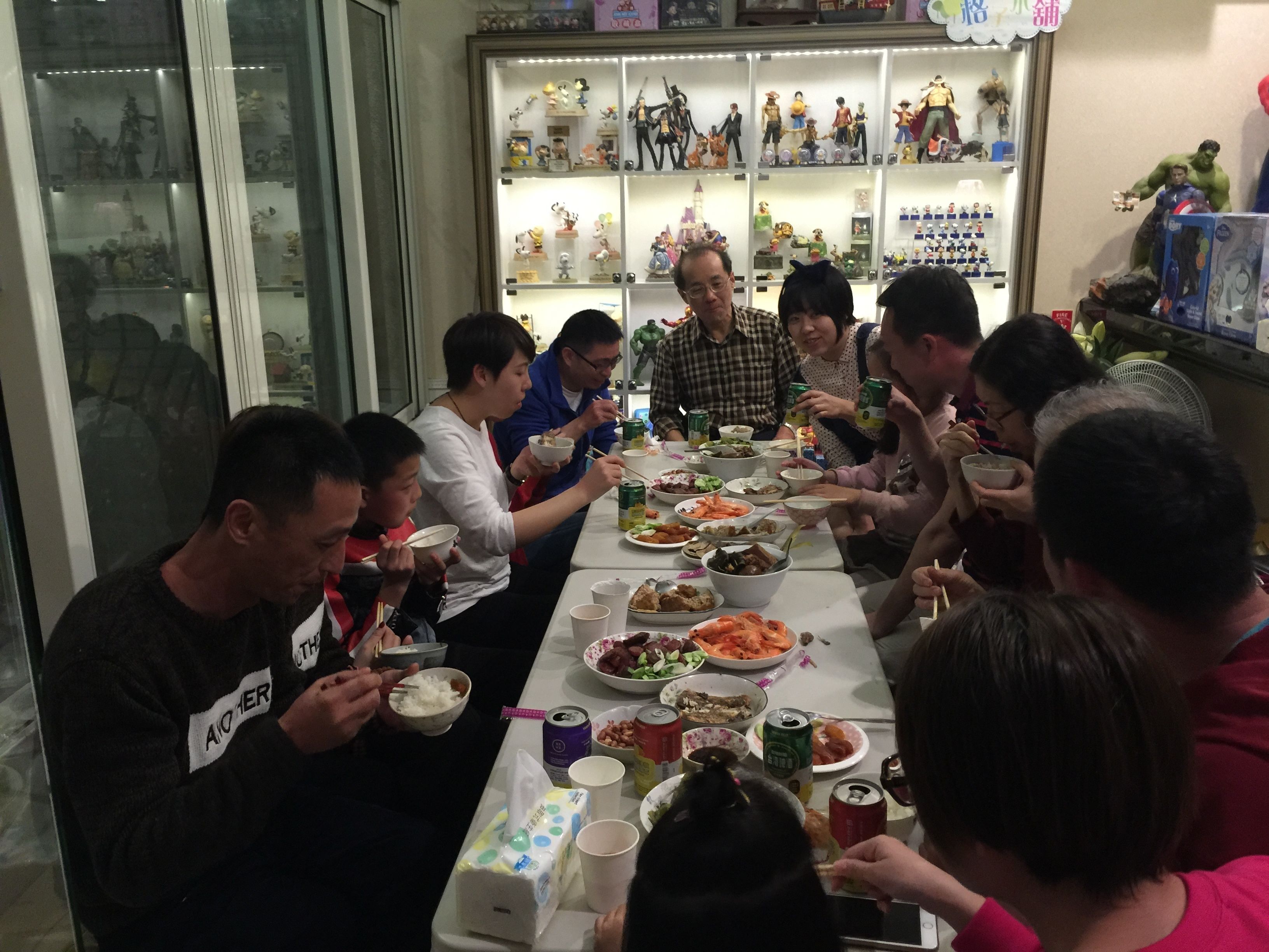 Un grupo de personas cenando en una mesa con varios platos y bebidas.