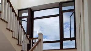 A staircase with wooden steps and white railings, leading to a landing with large windows. - Mallorca B&B (Taitung)
