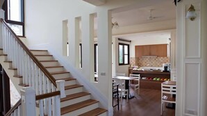 A spacious kitchen with wooden cabinets and a dining area with white chairs. - Mallorca B&B (Taitung)