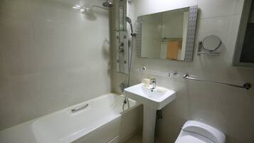 Un baño con bañera, lavamanos, inodoro, ducha, espejo y toallero.