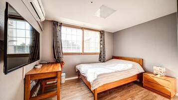 A bedroom with a wooden bed, a desk, and a TV.