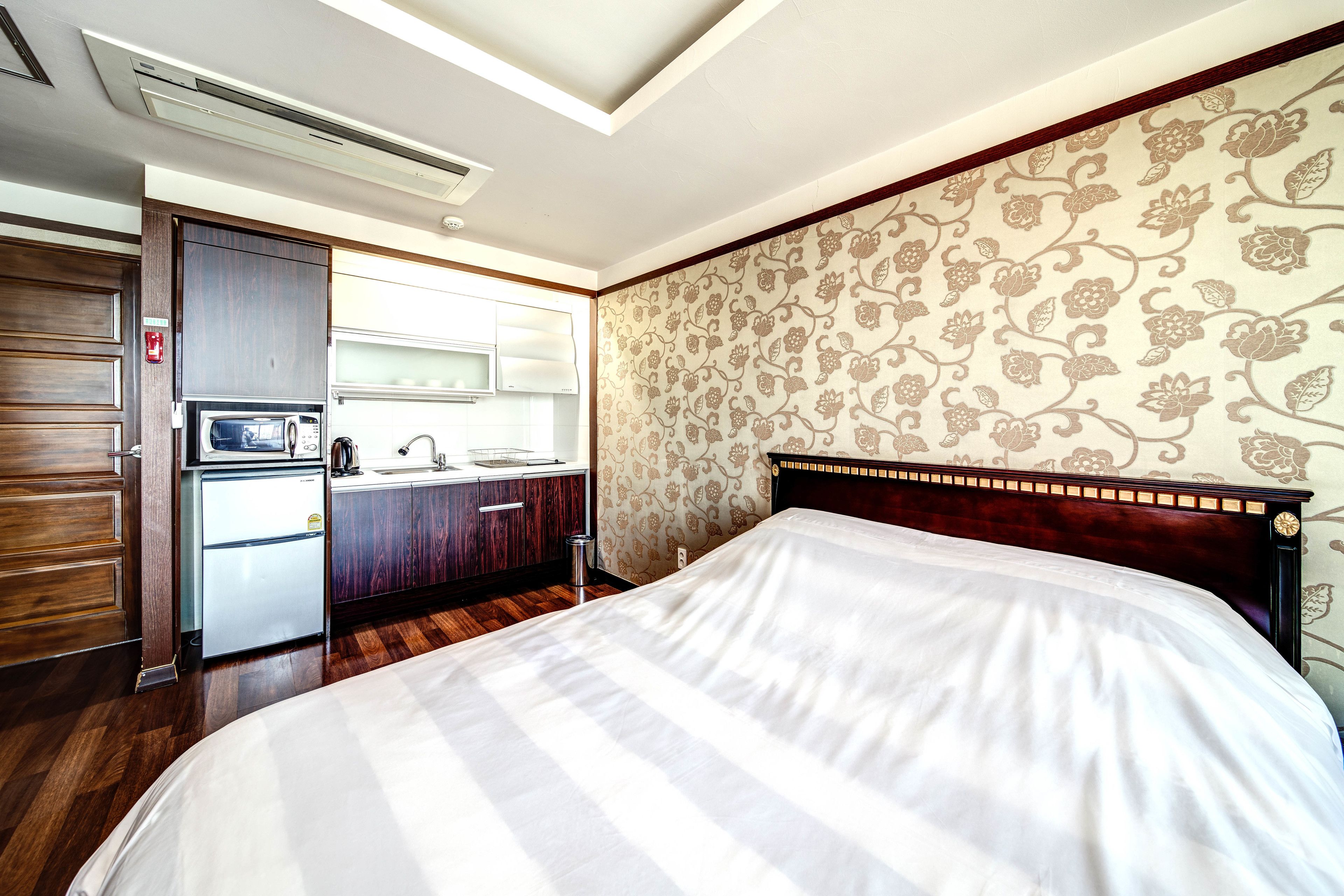 A hotel room with a bed, a kitchenette, and a bathroom.