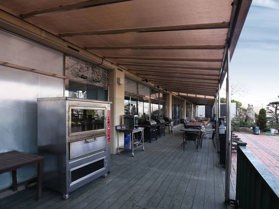 An outdoor patio with a covered seating area, a commercial oven, and grilling equipment.
