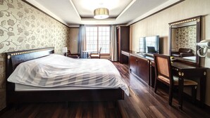 Una habitación de hotel con una cama grande, un escritorio, una silla, un televisor y un espejo.