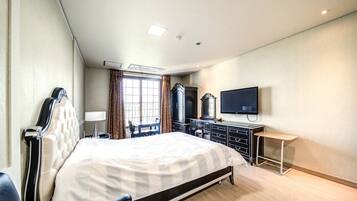 A hotel room with a large bed, a desk, a TV, and a wardrobe.