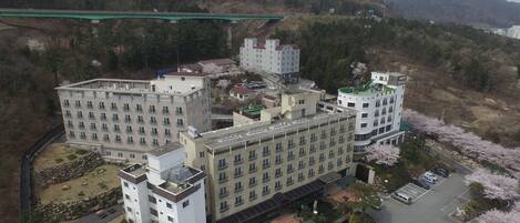 Un hotel grande con varias edificaciones, estacionamiento y árboles de cerezo.