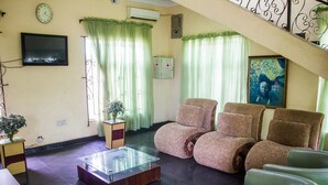 A living room with a sofa set, a coffee table, a TV, and a staircase. - Allonze Hotel (Ikorodu)