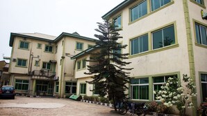 A multi-story building with large windows and a green-framed entrance. - Allonze Hotel (Ikorodu)