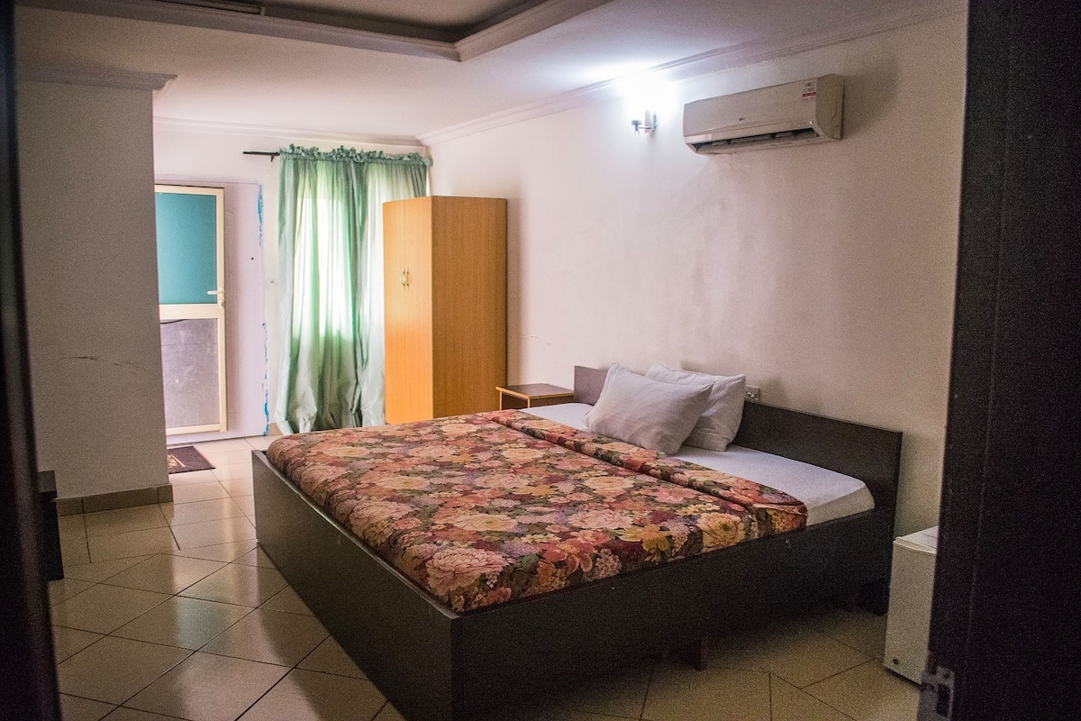Une chambre à coucher comprenant un lit, une table de chevet, une armoire et un appareil de climatisation.