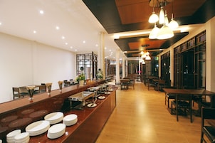 Buffet montado com várias estações de serviço, um balcão comprido com pilhas de pratos e diversos tipos de assentos.