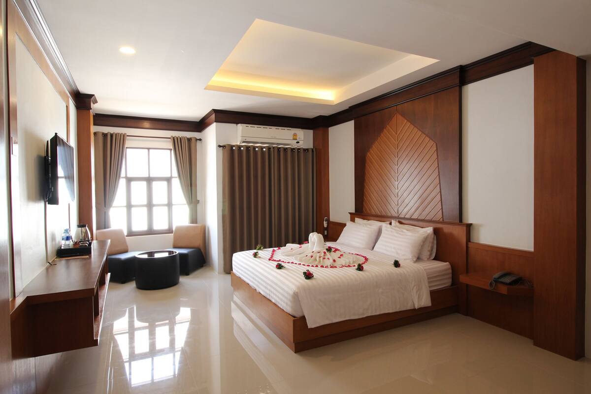 A modern hotel room with a large bed, a flat-screen TV, a desk, and a sofa.