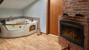 Una stanza con soffitto spiovente, vasca da bagno integrata, camino in mattoni e un lucernario.