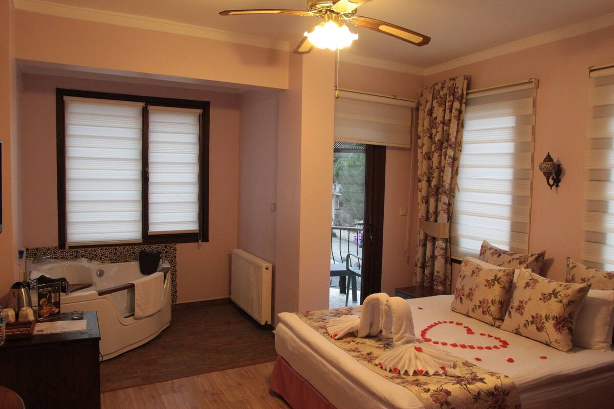 A bedroom with a bed, a bathtub, and a balcony.