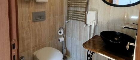 A bathroom with a toilet, a towel rack, a mirror, and a sink.