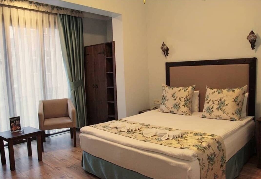 A bedroom with a bed, a chair, a small table, and a wardrobe.