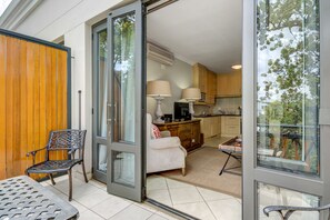 An open sliding glass door leading to a kitchen and dining area with a white chair, a table, and a sofa. - UniqueStay Oudehoek Apartment (Stellenbosch)