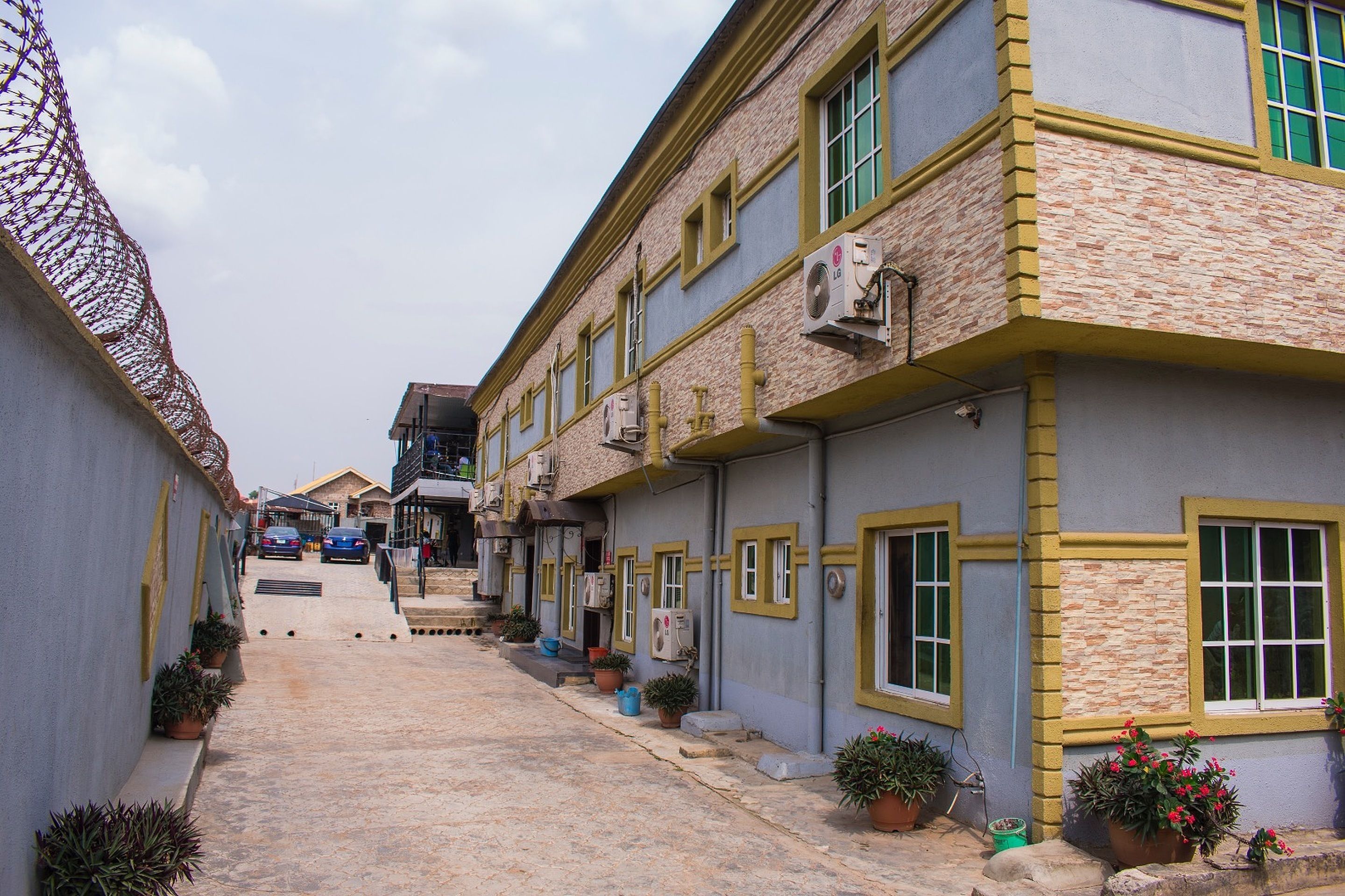Una calle estrecha flanqueada por edificios con fachadas de ladrillo y enlucido, bajo un cielo despejado.