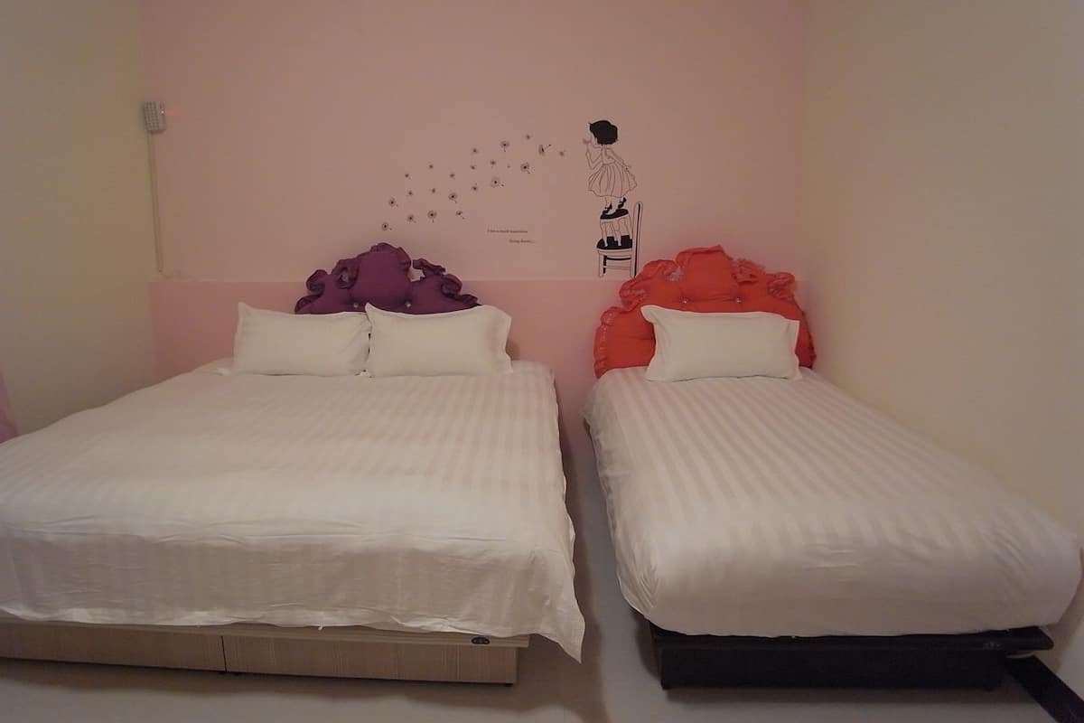 A room with two beds, each with a distinct headboard design and pillows.