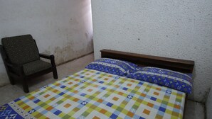 Ein Zimmer mit einem Bett, einem Sessel und einer schlichten Wand.
