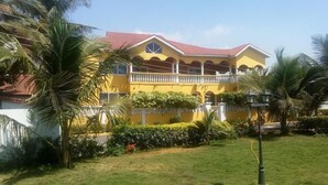 Un bâtiment jaune avec un toit rouge, entouré de verdure et de palmiers.