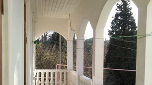 A covered balcony with white railings and a tiled floor, leading to a door. - White Guest House (Batumi)