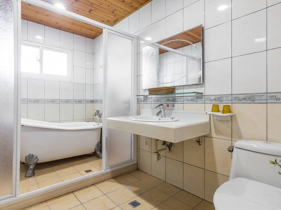 A bathroom with a bathtub, a sink, a toilet, and a mirror.