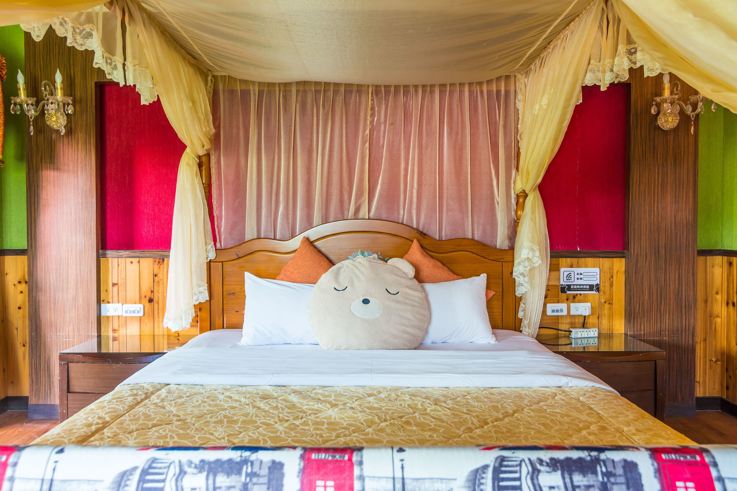 A bed with a canopy, a teddy bear pillow, and a bedspread with a cityscape design.