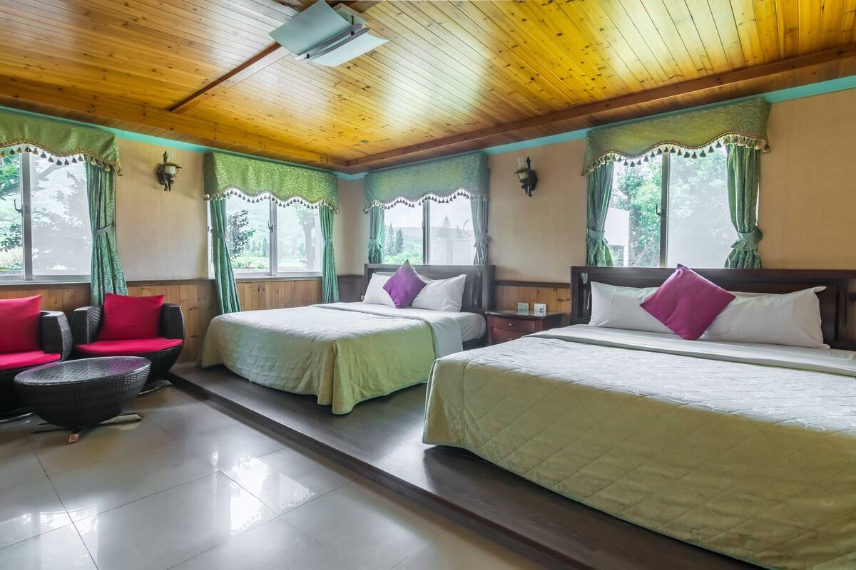 A hotel room with two beds, a sofa, and a small table.
